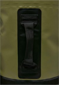 Grønn vanntett bag med teksturert overflate, svart stropp og kontrastfarge i svart rundt håndtaket. Holdbart og funksjonelt design.