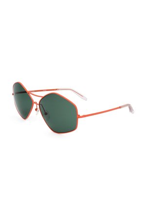 Occhiali da sole con sottili montature in metallo arancione e grandi lenti di forma esagonale irregolare verde scuro e terminali trasparenti per le aste.