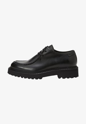 Chaussures derby en cuir noir au fini lisse, bout rond et semelle en caoutchouc noir épaisse avec un motif de semelle prononcé.
