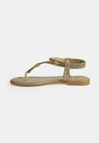 Flache Sandale in Goldoptik mit T-Riemen-Design, verziert mit Perlenakzenten, elastischem Knöchelband und flacher Sohle mit strukturiertem Finish.