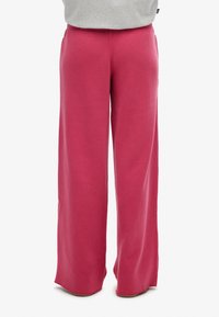 Pantaloni della tuta larghi, morbidi e rosa con elastico in vita. Realizzati in un tessuto testurizzato, presentano una vestibilità rilassata e un orlo dritto.