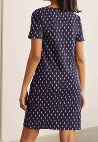 Mörkblå klänning med kort ärm och ett upprepande rosa paisley-mönster. Mjuk tyg, rak skärning, sidofåror för ökad rörelsefrihet.