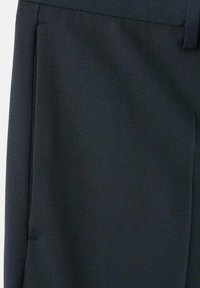 Zbliżenie na granatowe spodnie, pokazujące boczną kieszeń i pas z szlufką na pasek wykonane z gładkiej tkaniny.