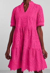 Roze katoenen jurk met een V-halslijn, korte mouwen, gelaagd ontwerp, geborduurde uitsnijdingen en gegolfde zoomafwerking.