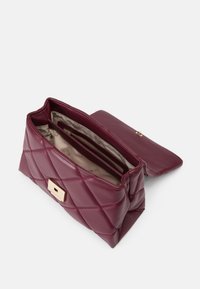 Bolso de mano de cuero burdeos acolchado con un cierre en tono dorado, que cuenta con un interior espacioso y un bolsillo con cremallera. Se abre con un acabado suave.