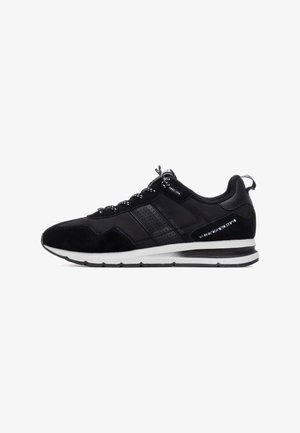 Zapatos deportivos negros con un upper de ante y malla, que presentan cordones negros y blancos, una entresuela blanca y una suela negra texturizada.
