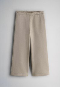 Bēšas plašas, uz augšu saīsinātas bikses ar elastīgu jostu, izvietotas plakani uz gaiši pelēka fona.