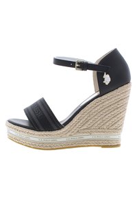 Sandalo wedge nero con tacco in juta intrecciata, caratterizzato da una larga fascia in tessuto nero e una fibbia regolabile alla caviglia. Dettaglio del logo impreziosito.