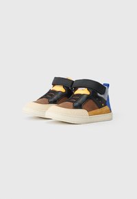 Par de ténis de cano alto multicoloridos para crianças com fechos de velcro pretos, painéis castanhos e amarelos, solas beges e detalhes azuis no calcanhar.