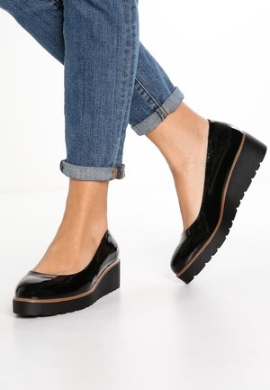 Sorte platform sko i laklæder med rundet tå, brun detalje langs sålen og tekstureret gummisål, kombineret med opkørt denim.