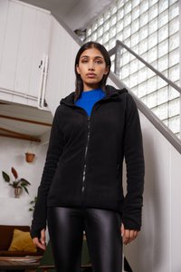 Zwarte fleece jack met een ritssluiting aan de voorkant, een capuchon en zijzakken, gedragen over een blauw geribd gebreid T-shirt. Model gecombineerd met zwarte leggings.