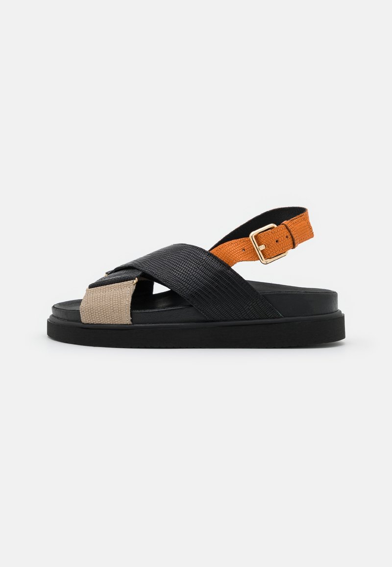 Sandale texturée noire et beige avec des brides croisées, une boucle orange réglable au talon et une semelle plate pour le confort.