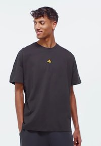 Sort kortærmet t-shirt lavet af bomuld, med et lille gyldent logo på brystet, rund halsudskæring og afslappet pasform.