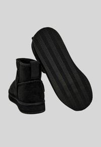 Stivaletti neri in camoscio con suola in gomma testurizzata a motivo spina di pesce. Dotati di piccolo tirante posteriore per una facile calzata.