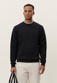 Μαύρο φούτερ από βαμβακερό μείγμα με ριμπ λαιμόκοψη και μανσέτες. Διαθέτει μικρό κόκκινο λογότυπο στο στήθος. �Φοριέται με ανοιχτόχρωμο παντελόνι.