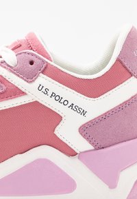 Růžovo-bílá sportovní obuv s texturovanou látkou a hladkými doplňky, s logem na boku a vícestupňovým designem podešve.