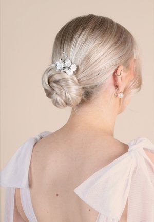Silberner Haarschmuck mit weißen Blumendetails, in einem niedrigen Dutt gesteckt. Hat eine glatte Textur und zarte Perlenakzente.