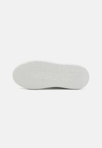Fehér gumis sneaker talp, melyen textúrált tapadó minta és domború logó található. A dizájn minimalista, további színek vagy kiemelések nélkül.