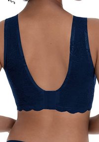 Bralette in pizzo blu navy con schiena a basso scoop, spalline larghe e bordi scallopati. Motivo floreale testurizzato su tutta la stoffa.