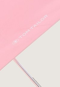 Roze parapludak met wit "TOM TAILOR" logo en zichtbare metalen schacht op een lichte achtergrond.
