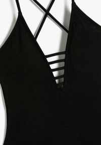 Maillot de bain noir avec un décolleté en V profond, des bretelles croisées et des détails de bretelle horizontale, fabriqué en tissu texturé.
