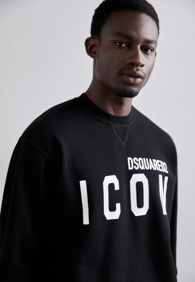 Juoda sweatas, turintis apvalią kaklą, su baltais „ICON“ raidėmis ir prekės ženklu „DSQUARED2“ viršuje. Pagamintas iš minkštos medžiagos.