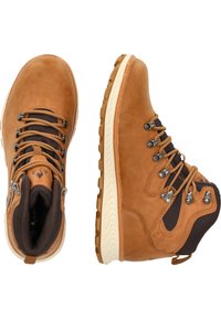 Bruna lädervandringsskor med en texturerad yta, utrustade med metallkrokar, bruna nätinslag och en gummisula med ett zickzack-mönster.