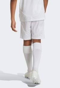 White athletic jersey and shorts, paired with knee-high white socks and cleats. Smooth fabric with a relaxed fit.