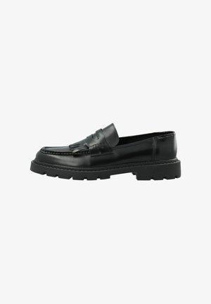 Black leather loafer with chunky rubber sole, fringe detail on vamp, and stitched moc toe, viewed from the side on a white background.