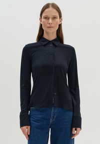 Navy long-sleeve button-up shirt in a smooth, stretchy fabric. Features a classic collar and button front, with fitted cuffs.