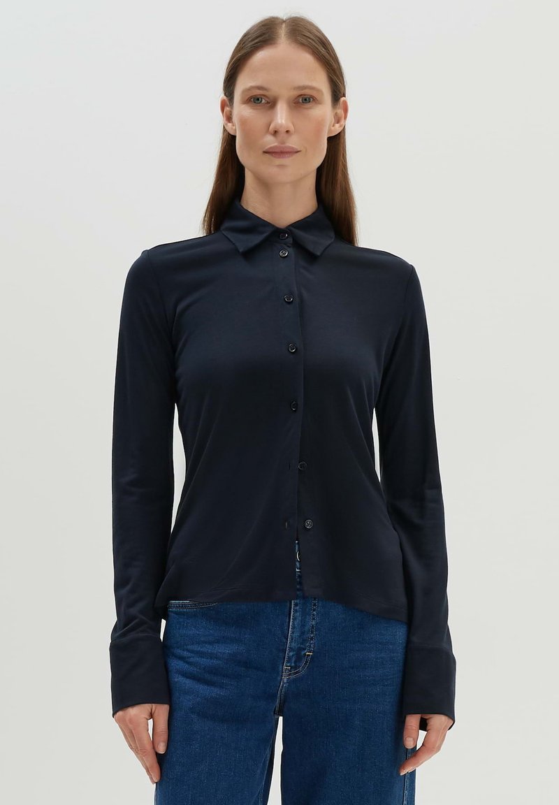 Navy long-sleeve button-up shirt in a smooth, stretchy fabric. Features a classic collar and button front, with fitted cuffs.