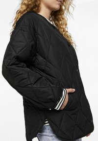 Black quilted jacket featuring a diamond pattern, contrasting striped cuffs, and side pockets. The material appears smooth and puffy.