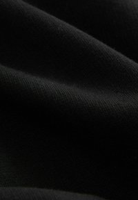 Schwarzer Stoff mit glatter Textur, der subtile Farbveränderungen und ein einheitliches Gewebemuster aufweist. Leicht zerknittertes Aussehen.