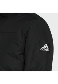 Černá zateplená bunda s texturovanou tkaninou, se zipovým uzávěrem a vyšitým bílým logem Adidas na čtvercovém nápletu na rukávu.