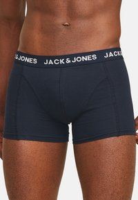 Marineblauwe boxershorts met een zachte textuur, voorzien van een witte elastische tailleband met merklogo en contrasterende stikdetails.