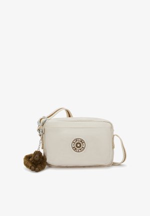 Borsa a tracolla color crema in tessuto morbido con chiusura a zip, caratterizzata da una toppa rotonda con logo e un portachiavi a forma di scimmia marrone.