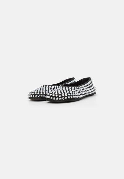 Black flats covered with large silver studs, featuring a rounded toe and low, flexible sole. Smooth fabric texture with a decorative pattern.