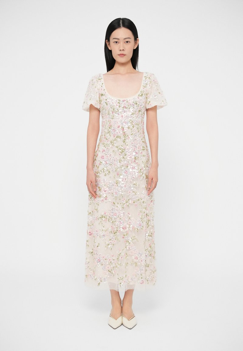 Dlhé priesvitné šaty v bledo béžovej farbe s kvetinovou výšivkou v ružovej a zelenej farbe. Majú krátke nafúknuté rukávy a štvorcový výstrih.