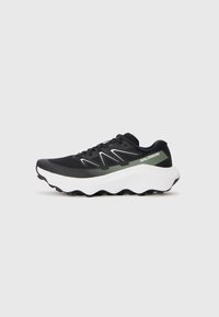 Baskets de sport noires avec tige en mesh, semelle intermédiaire blanche et accents verts. Présente une semelle extérieure texturée pour une meilleure adhérence et des coutures blanches contrastantes.