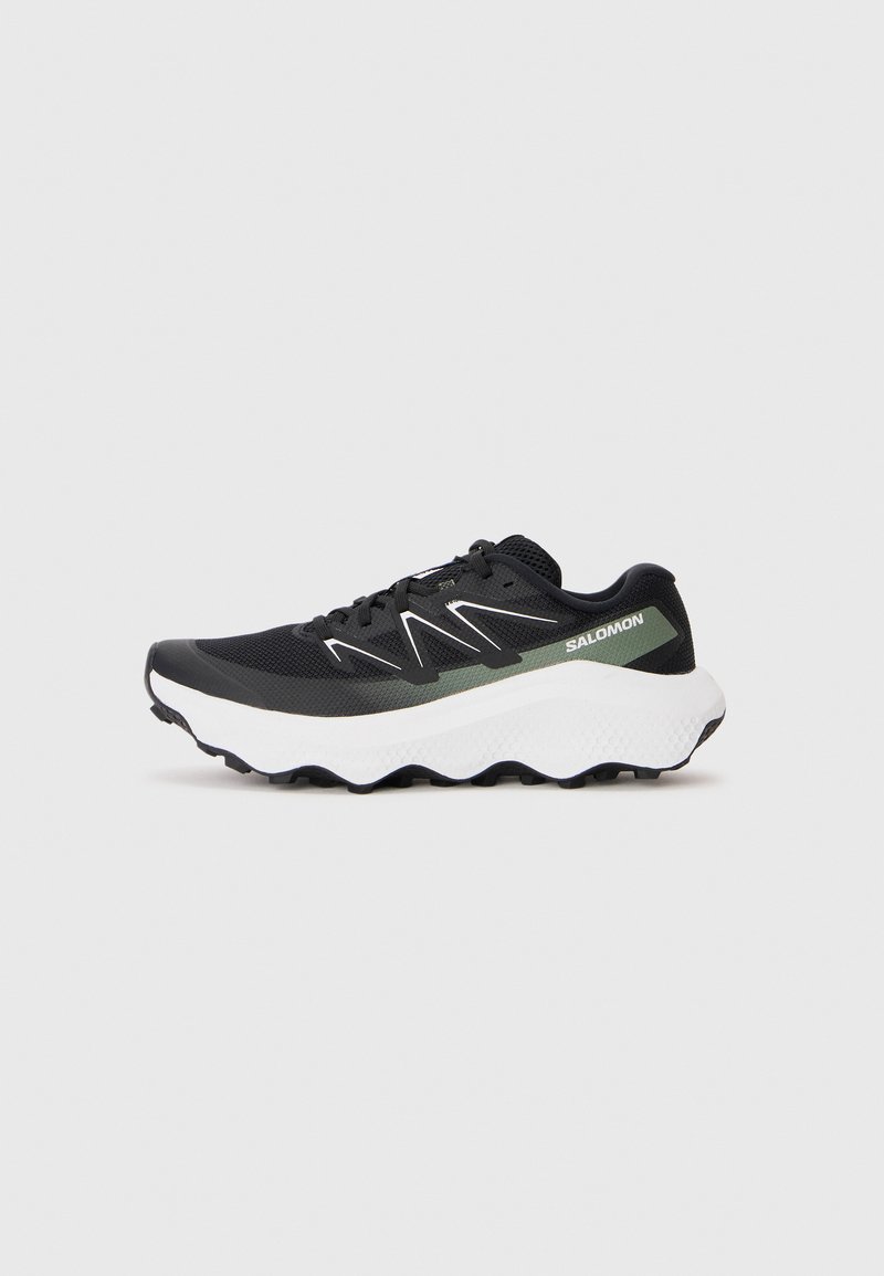 Shoe sport negru cu partea superioară din plasă, talpă intermediară albă și accente verzi. Prezintă o talpă texturată pentru aderență și cusături albe contrastante.
