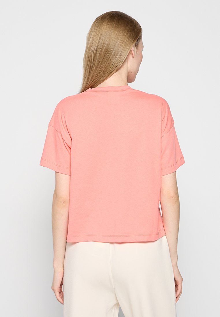 T-shirt à manches courtes de couleur corail rose, avec un col rond et une coupe décontractée, présenté de dos, mettant en avant une texture de tissu lisse.
