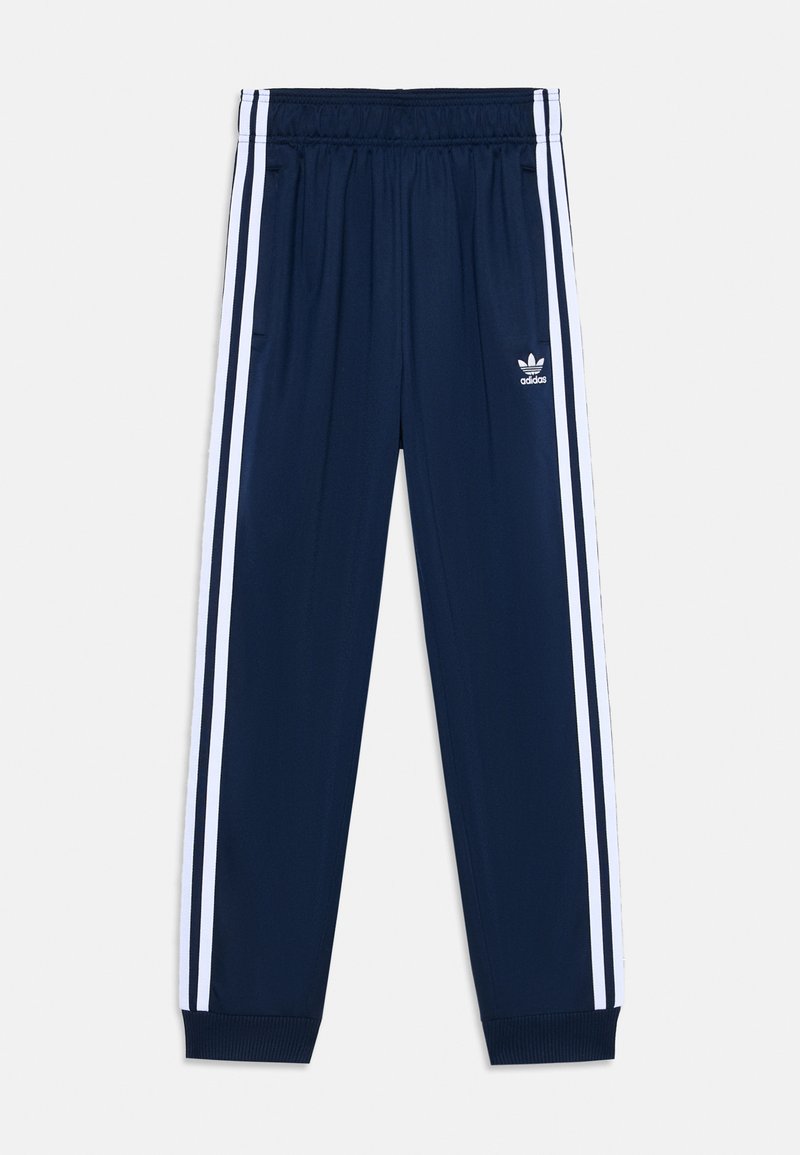 Tamsiai mėlynos sportinės kelnės su baltomis šoninėmis juostelėmis, elastingu liemeniu, įrimais ant rankogalių ir maža Adidas logotipu ant kairiojo šlaunies.