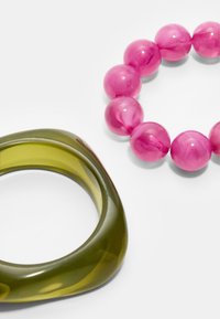 Bracciale in resina verde trasparente con curve fluide accanto a un braccialetto con perle rosa, caratterizzato da perle sferiche lucide e una marbling visibile.