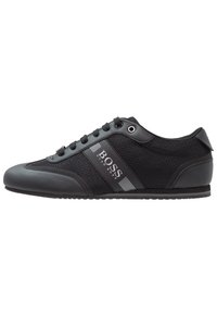 Black athletic shoe featuring a mix of smooth synthetic leather and breathable fabric, with a logo accent and traditional lace-up design.