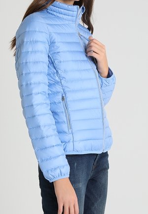 Veste matelassée bleu clair avec un design de coutures horizontales, col montant et poches zippées. Le tissu semble lisse et léger.