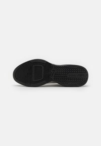 Schwarze Schuhsohle aus strukturiertem Gummi für Grip, mit einem gemusterten Profildesign, das ein zentrales rechteckiges Element und Branding-Details aufweist.