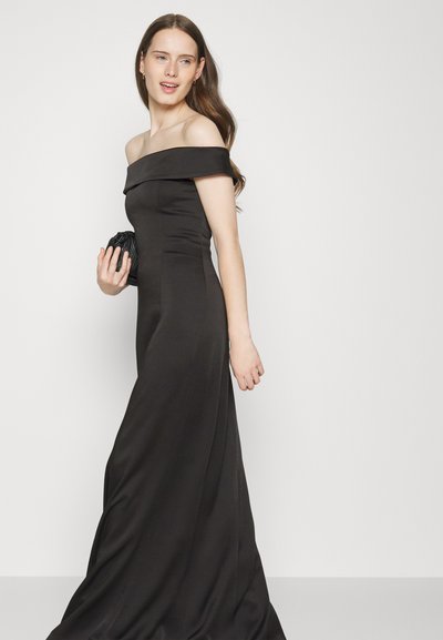 Abito da sera nero off-the-shoulder con corpino aderente, gonna fluida e texture liscia e setosa. Accessoriato con una piccola clutch texture.