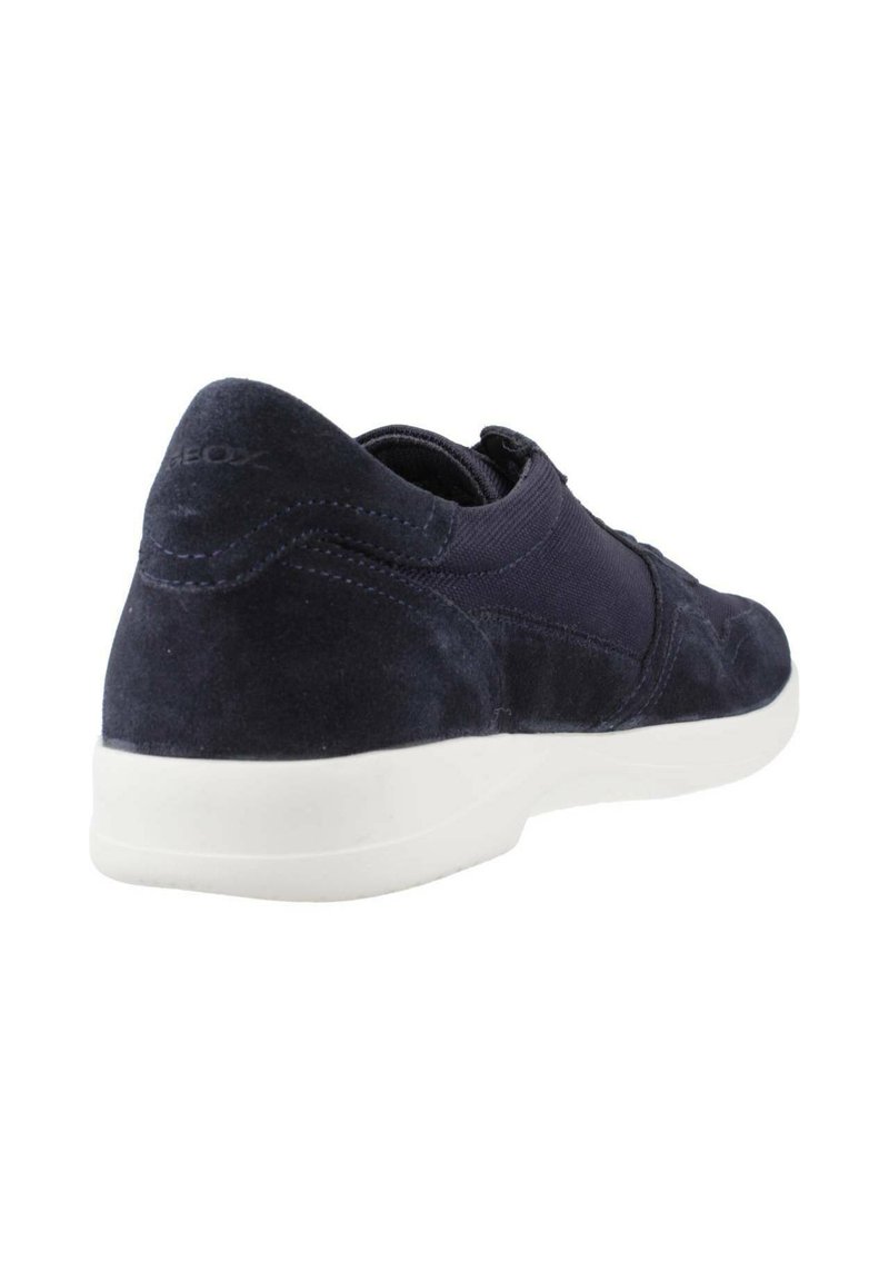 Zapatillas de gamuza en color navy con suela de goma blanca, que presentan paneles elásticos y una punta redondeada. Detalles sutiles del logo en el talón.