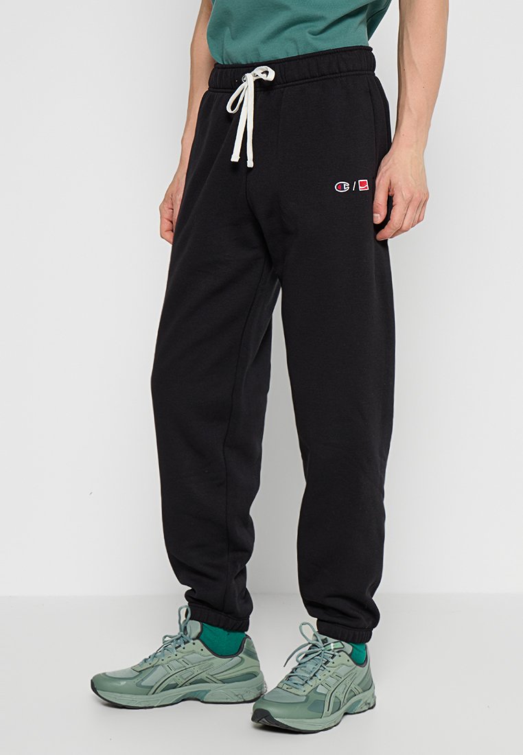 Pantaloni della tuta neri con vita elastica e coulisse, dotati di tasche laterali e un piccolo logo ricamato sulla coscia.