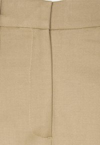 Beige op maat gemaakte broeken met een gladde textuur, strakke lijnen en een enkele achterzak, vergezeld van een subtiele stikselafwerking.